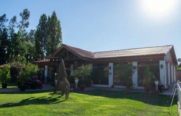 Casona rodeada de prado y árboles en un día soleado
