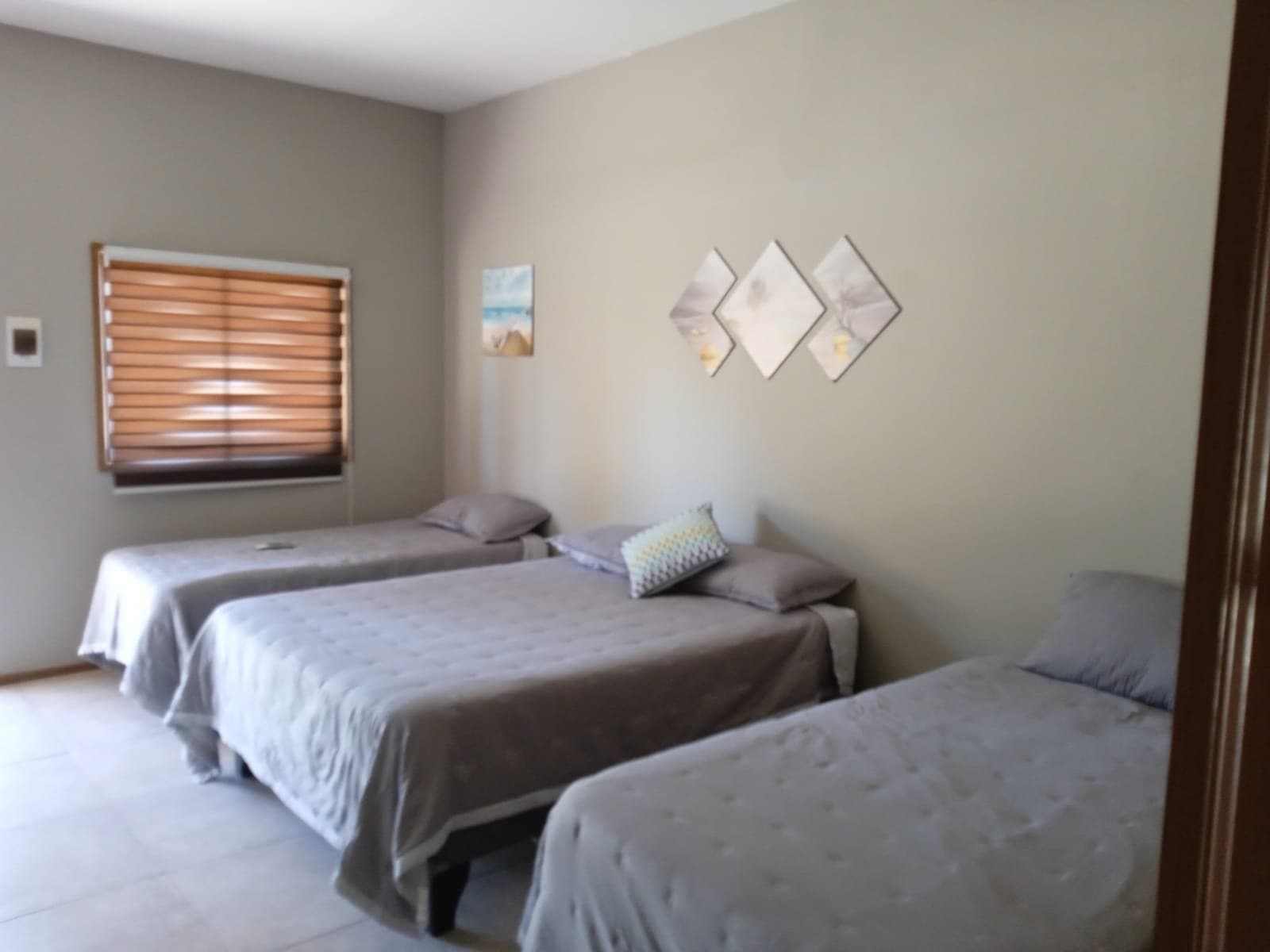Habitación con tres camas y ventana con cortina