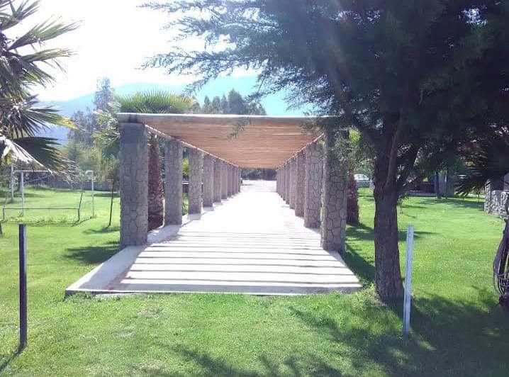 Pasillo de los novios bajo una pérgola de troncos en el jardín