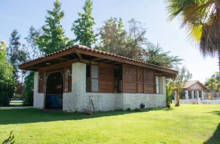 Quincho de piedra y madera en medio del jardín